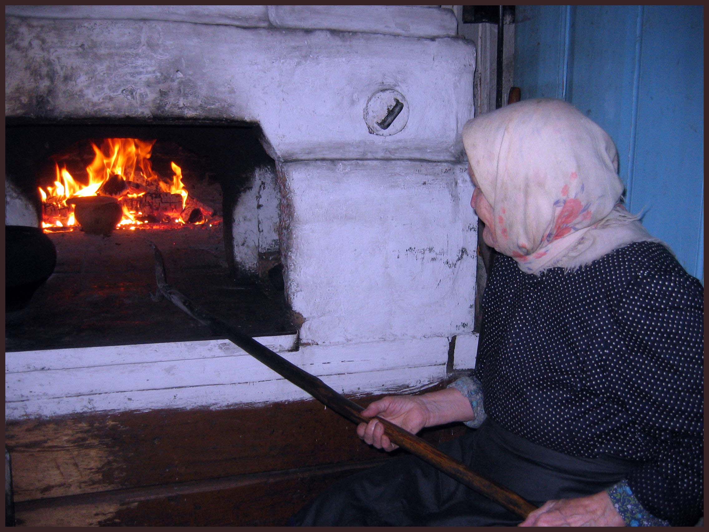 Милено в печи фото. Бабушка у печки. Старушка у печи. Бабушка печет. Печка топится.