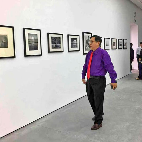 Чарлз Джин проходит по выставке фотографий из своей коллекции под названием «Морская серия» (“Sea Series”) в Sanya Contemporary Museum в Хайнане, 2017