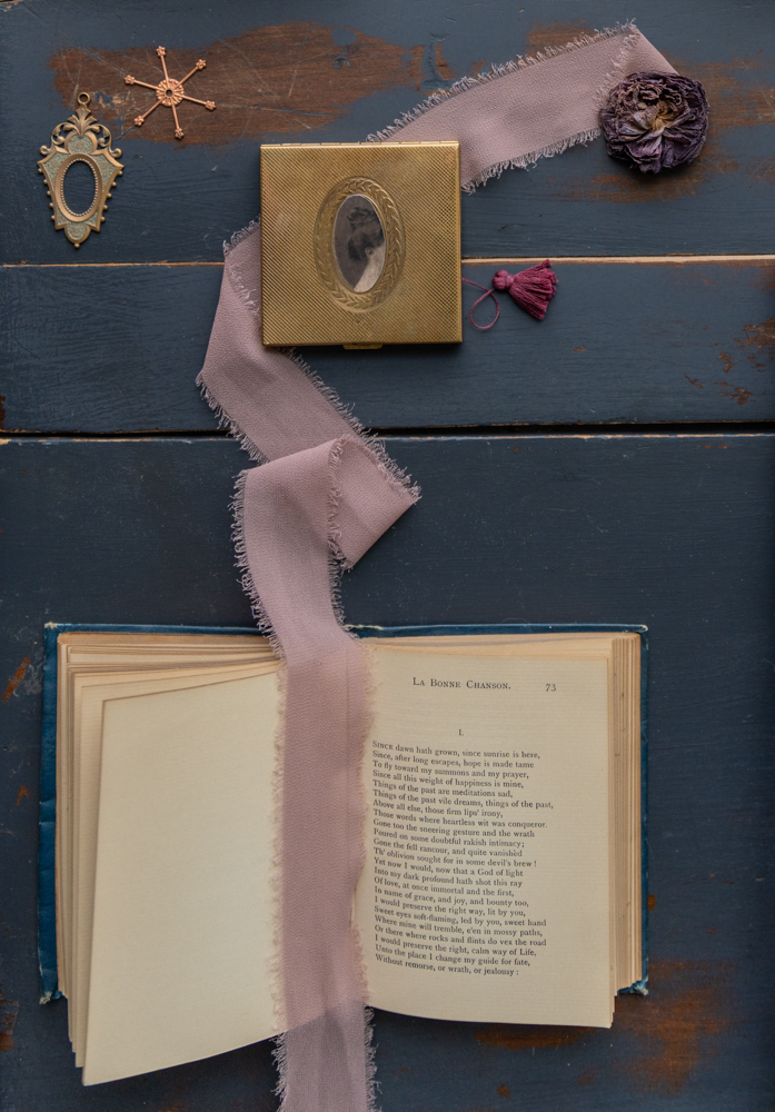 Фотографический объект, состоящий из старинной пудреницы, издания стихов Верлена 19 века, старинной ленты, найденных предметов и высушенного лютика. © Кристин Клафф