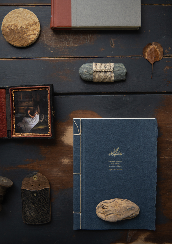 Автопортрет в футляре для тинтайпа, обернутый камень Тима Уиттена, сухой лист, известняк, коряга и любимый журнал с вечной цитатой Ральфа Уолдо Эмерсона: «Живите на солнце, купайтесь в море, пейте свежий воздух». © Кристин Клафф